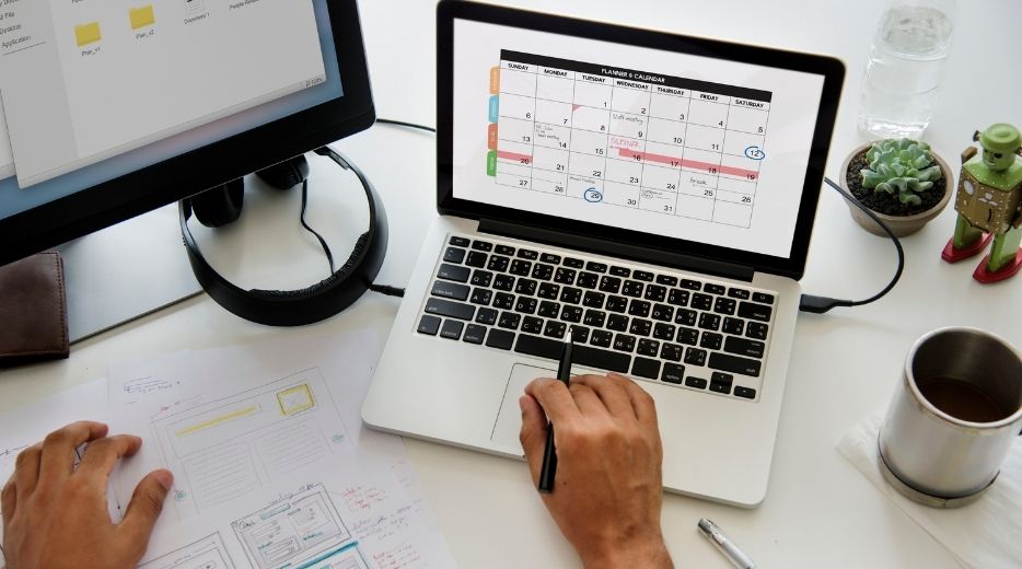 Pessoa olha calendário no notebook enquanto faz a escrituração de PIS e COFINS